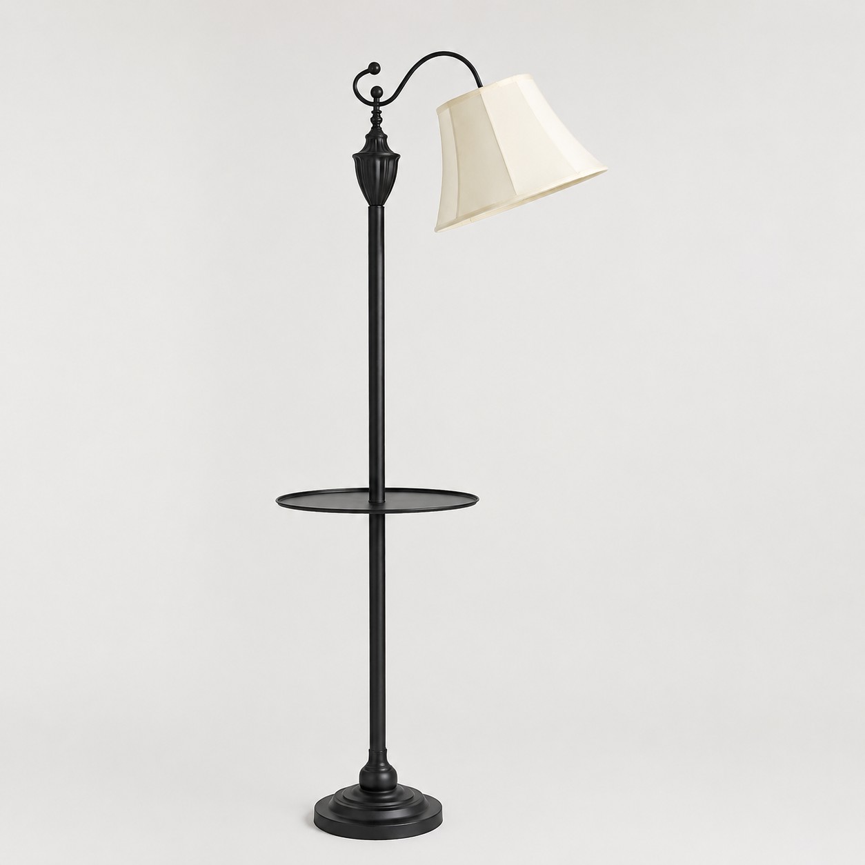 Full view of vintage black arc floor lamp with beige fabric shade and round side table